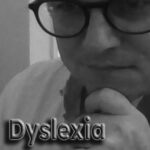 Black-and-white close-up of Patrick wearing glasses with text overlay “Dyslexia,” representing life with dyslexia and its impact on identity.